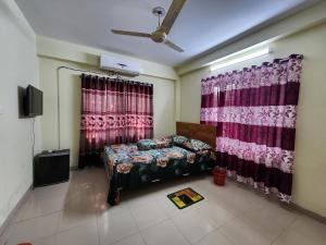 达卡Aaira guest house的一间卧室配有床和窗帘以及电视