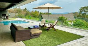 珍南海滩Aroha Seaview Villa - Private Pool -的一个带桌子和遮阳伞的庭院和一个游泳池