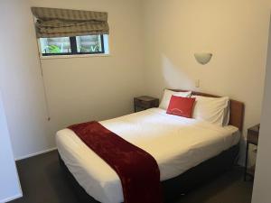 惠灵顿Ascot Motor Lodge的一间卧室配有一张红色枕头的床