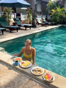 吉利特拉旺安White Coconut Resort的坐在游泳池里吃菜的女人