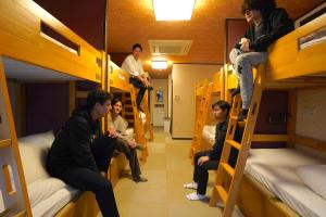 东京COGO Ryogoku的一群男人坐在一个房间里双层床上