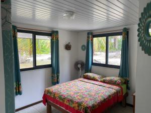 RotoavaKoriKori House Fakarava的一间卧室设有一张床和两个窗户。
