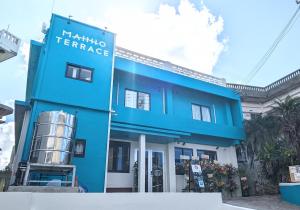 宫古岛MAHHO TERRACE MIYAKO的蓝色建筑,上面标有读到kushima露台的标志