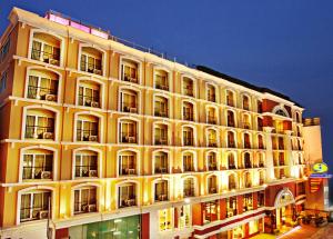 芭堤雅市中心Intimate Hotel Pattaya - SHA Extra Plus的一座黄色的大建筑,晚上有很多窗户