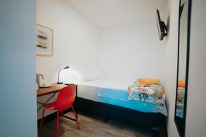 危地马拉Tequila Sunrise Hostel的一间卧室配有一张床、一张桌子和一把红色椅子