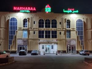 Sayḩ adh DhabiMarhabaa hotel的一座大型建筑,晚上有汽车停在外面