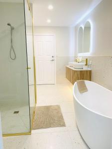 黄金海岸Deluxe Queen Studio Fully Self Contained- Living, kitchenette, laundry, bedroom, bathroom, parking, Wifi, - Free shuttle Service的带浴缸和玻璃淋浴间的浴室。