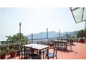 穆索里Hotel Valley View, Mussoorie的阳台上的一排桌椅