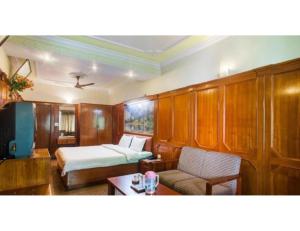 穆索里Hotel Valley View, Mussoorie的一间卧室配有一张床、一张沙发和一张桌子