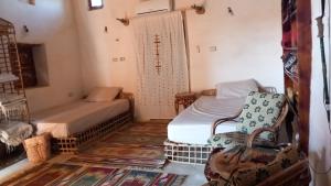 锡瓦مراقي سيوة Maraqi Siwa的一间设有两张床和两把椅子的房间