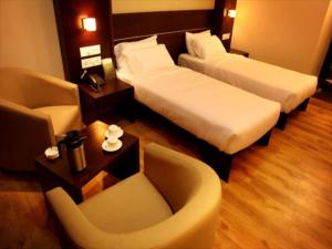 迈索尔SUNFLOWER HOTEL的酒店客房,配有两张床和椅子