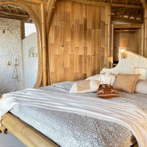 珀尼达岛Camanta Penida - Adult Only的一间卧室配有一张带木墙的大床