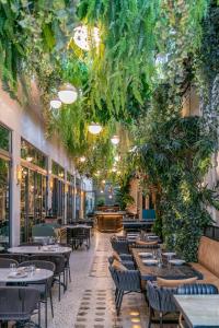 雅典Gatsby Athens的一间设有桌椅的餐厅,种植了植物