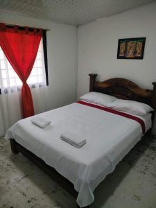 NorcasiaCasa Hostal M&M的卧室配有一张白色大床和红色窗帘