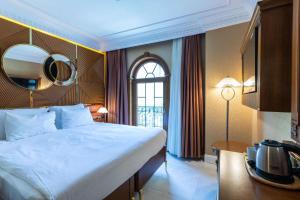伊斯坦布尔Wyndham Istanbul Old City的一间卧室配有一张大床,墙上设有一面镜子