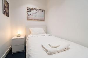 墨尔本2 BD Luxury apartment at heart of Docklands with 85" flat TV & Free Carpark的一间小卧室,配有白色的床和床头柜
