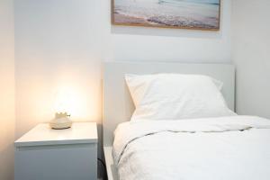 墨尔本2 BD Luxury apartment at heart of Docklands with 85" flat TV & Free Carpark的卧室配有白色的床和带台灯的床头柜。
