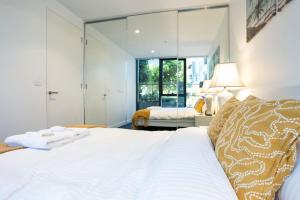 墨尔本2 BD Luxury apartment at heart of Docklands with 85" flat TV & Free Carpark的卧室设有一张白色大床和一扇窗户。