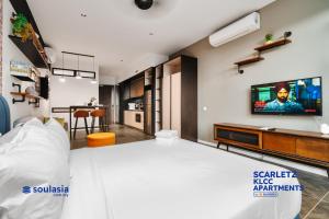 吉隆坡Scarletz KLCC Apartments by soulasia的卧室配有一张床,墙上配有电视。