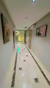 利雅德السعادة سويت - الملز الرياض Saada Suites Serviced Apartments的长长的走廊,铺有瓷砖地板,墙上挂有绘画作品