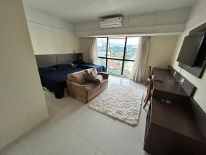 马瑙斯Tropical Executive Flat Vista Incrível para a Orla的一间卧室配有一张床、一张沙发和一个窗口