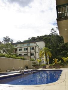 彼得罗波利斯Estúdios no Resort Granja Brasil em Itaipava的一个带椅子的游泳池和一个背景建筑