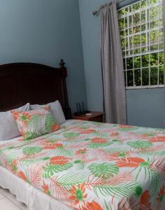 卡斯特里Bougainvillea Apartments的一张带五颜六色的被子和窗户的床