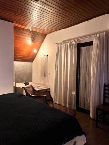 伊泰帕瓦Jardim Secreto - Itaipava的一间卧室配有一张床、一张书桌和一个窗户。