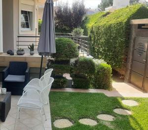 帕特雷Villa Ariadni的一个带遮阳伞、椅子和草地的庭院