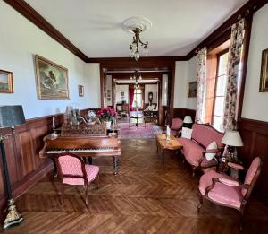 巴尼奥勒德日洛恩Chateau du Gue aux Biches的客厅配有钢琴和椅子