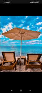 帕拉塔蒙Galazio Seaside Luxury Rooms & Coffee Shop的海滩上的两把椅子和一把遮阳伞