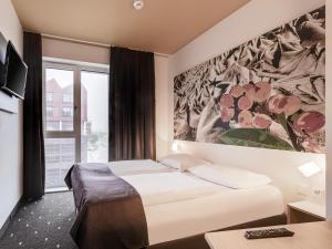 不莱梅B&B Hotel Bremen-Überseestadt的酒店客房设有两张床和窗户。
