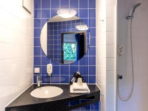 汉堡汉堡-阿尔托那B&B酒店的蓝色瓷砖浴室设有水槽和镜子