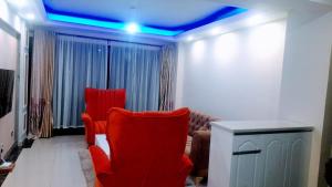 内罗毕the perfect affordable apartments的客厅设有红色椅子和蓝色天花板