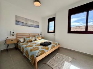 厄尔梅达诺Chalet Adosado El Medano的一间卧室配有一张床、一张书桌和一个窗户。