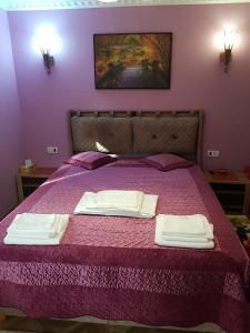布什泰尼Casa Nicolas Busteni的紫色卧室配有一张床和两条毛巾