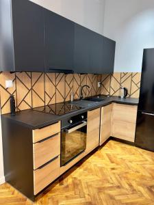 格涅兹诺Apartamenty In Centro by 3 maja的厨房配有黑色台面和木制橱柜