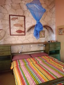 Calheta Do MaioResidenz Stella Maris Apartment Strela的一间卧室设有一张床和石墙