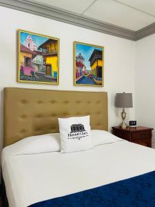 莱昂Hostal Clary的卧室配有一张白色床,墙上挂有两张照片