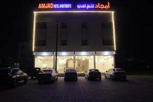 Al Ḩuwaylأمجاد للشقق الفندقية的停在大楼前的一组汽车