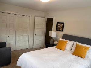 温尼伯Cozy Haven的一间卧室配有带白色床单和橙色枕头的床。