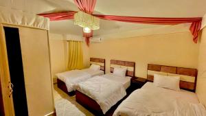 开罗Sami Holiday Inn - pyramids view Rooftop的一间卧室配有两张床和吊灯。