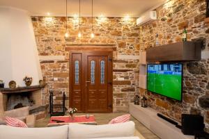 希俄斯ΠΕΤΡΙΝΟ ΣΠΙΤΙ ΣΤΟΝ ΚΑΜΠΟ ΧΙΟΥ的客厅设有石墙和电视。