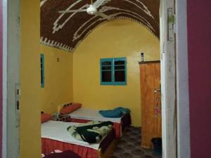 阿斯旺Azoz Nubian House的黄色间内带两张床的房间