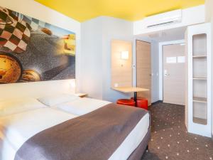 斯图加特B&B Hotel Stuttgart-Zuffenhausen的酒店客房设有一张床,墙上挂有绘画作品