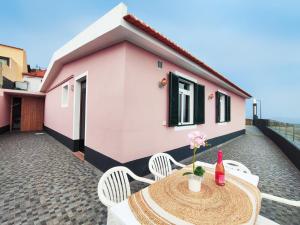马希库GATEONE AL Airport View House的一个带桌椅的庭院和一座粉红色的房子
