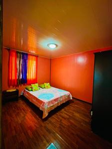 AfareaituTeraupoo Lodge Maison的一间卧室拥有橙色的墙壁,床上配有黄色枕头