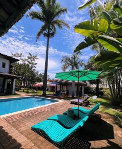 瓜鲁雅Pousada Casa Paradiso Guarujá的一个带2把躺椅和绿伞的游泳池