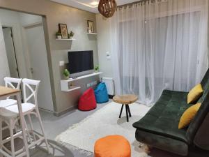 Boumhel El BassatineCoquette Appartement的客厅配有绿色沙发和电视