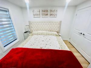 伦敦Holiday home with all season Swim spa & Pond view的卧室配有一张带红色毯子的白色床